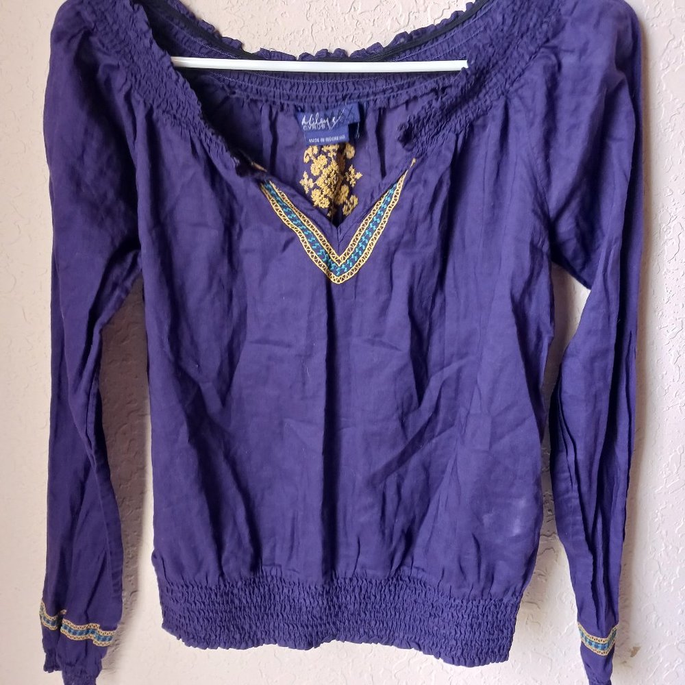 Purple, with gold and aqua color design stitching. Long sleeve crop top.
